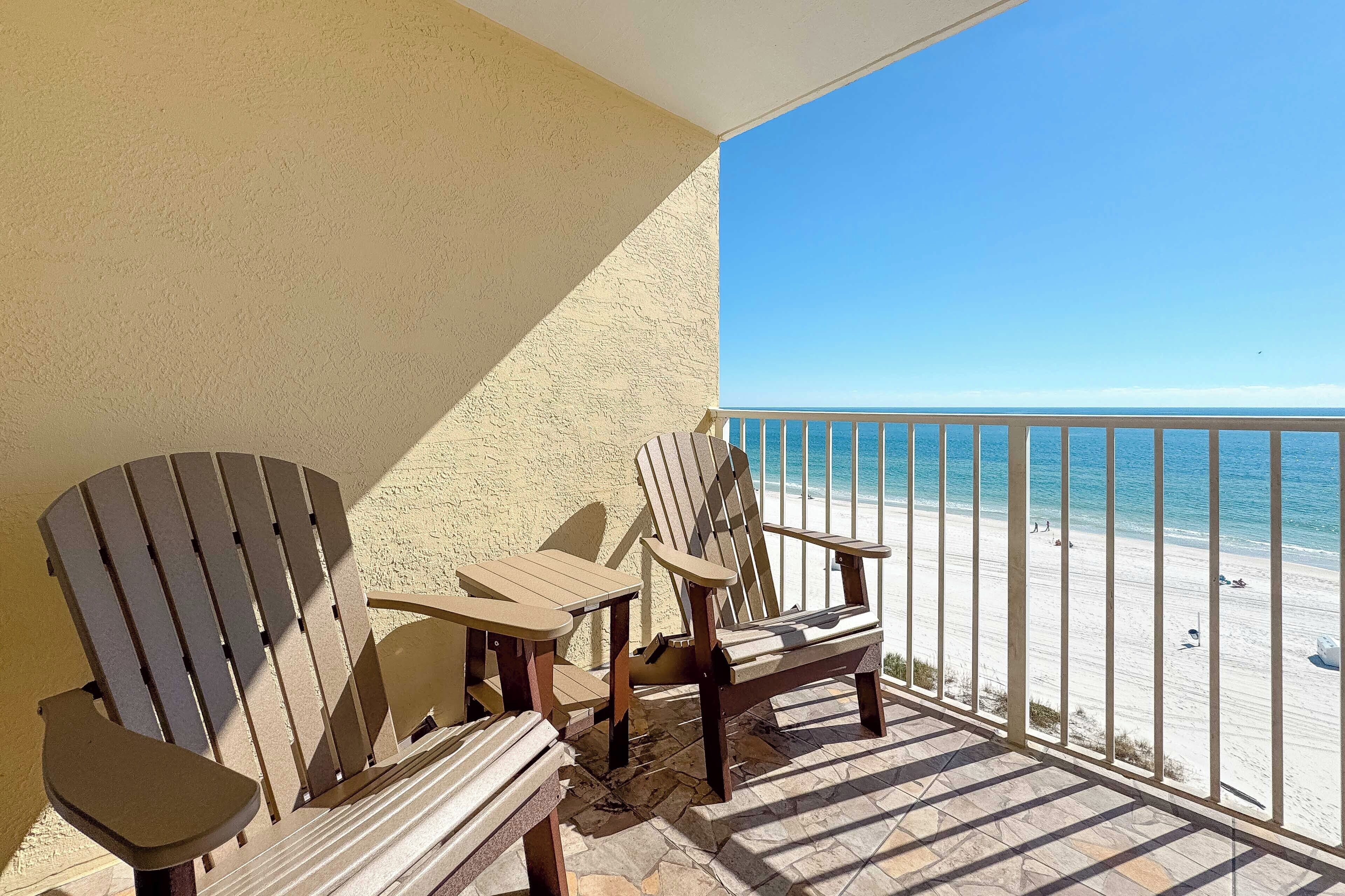 A balcony with Adirondack chairs and a view of the beach.