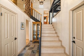 A staircase with a wooden finish, flanked by beige walls and doors, leading to an upper level.