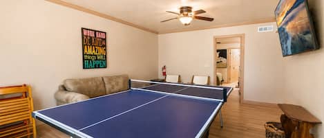 A room with two ping pong tables, a ceiling fan, and a motivational poster on the wall.