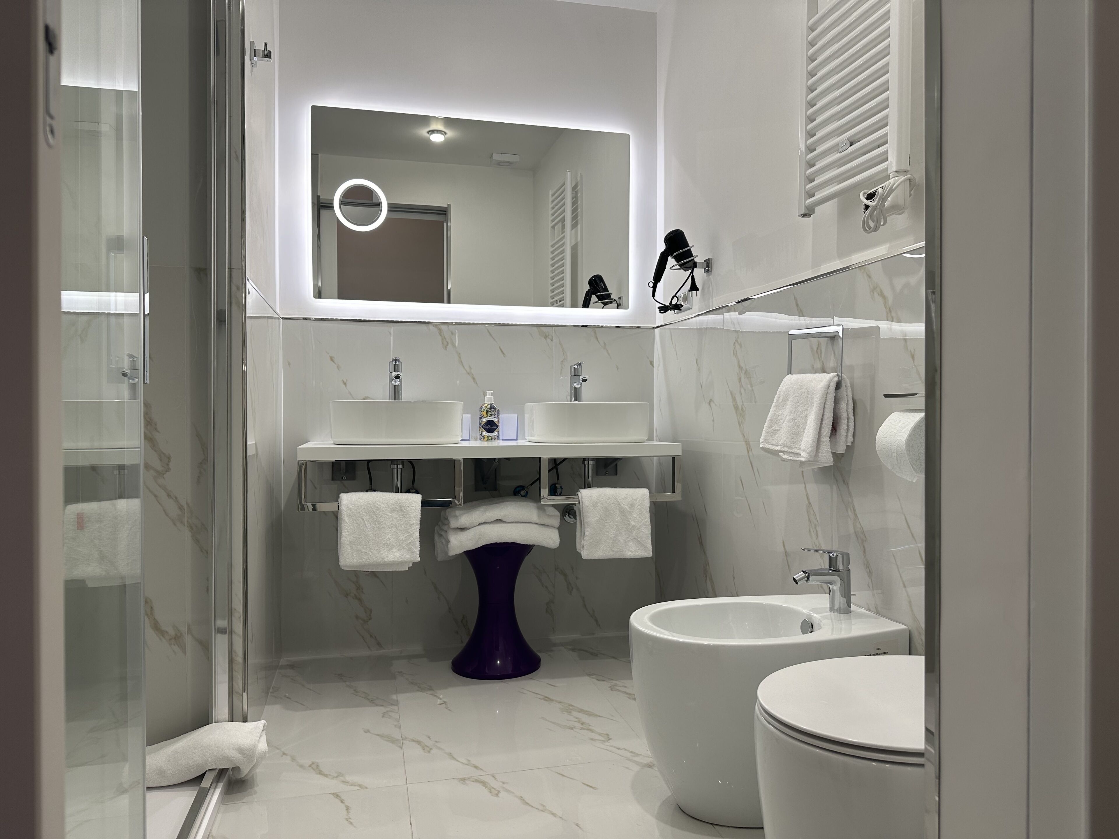 Ein modernes Badezimmer mit Duschkabine aus Glas, einem Standwaschbecken, einem Bidet und einer Toilette.