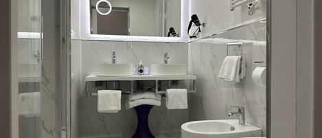 Ein modernes Badezimmer mit Duschkabine aus Glas, einem Standwaschbecken, einem Bidet und einer Toilette.