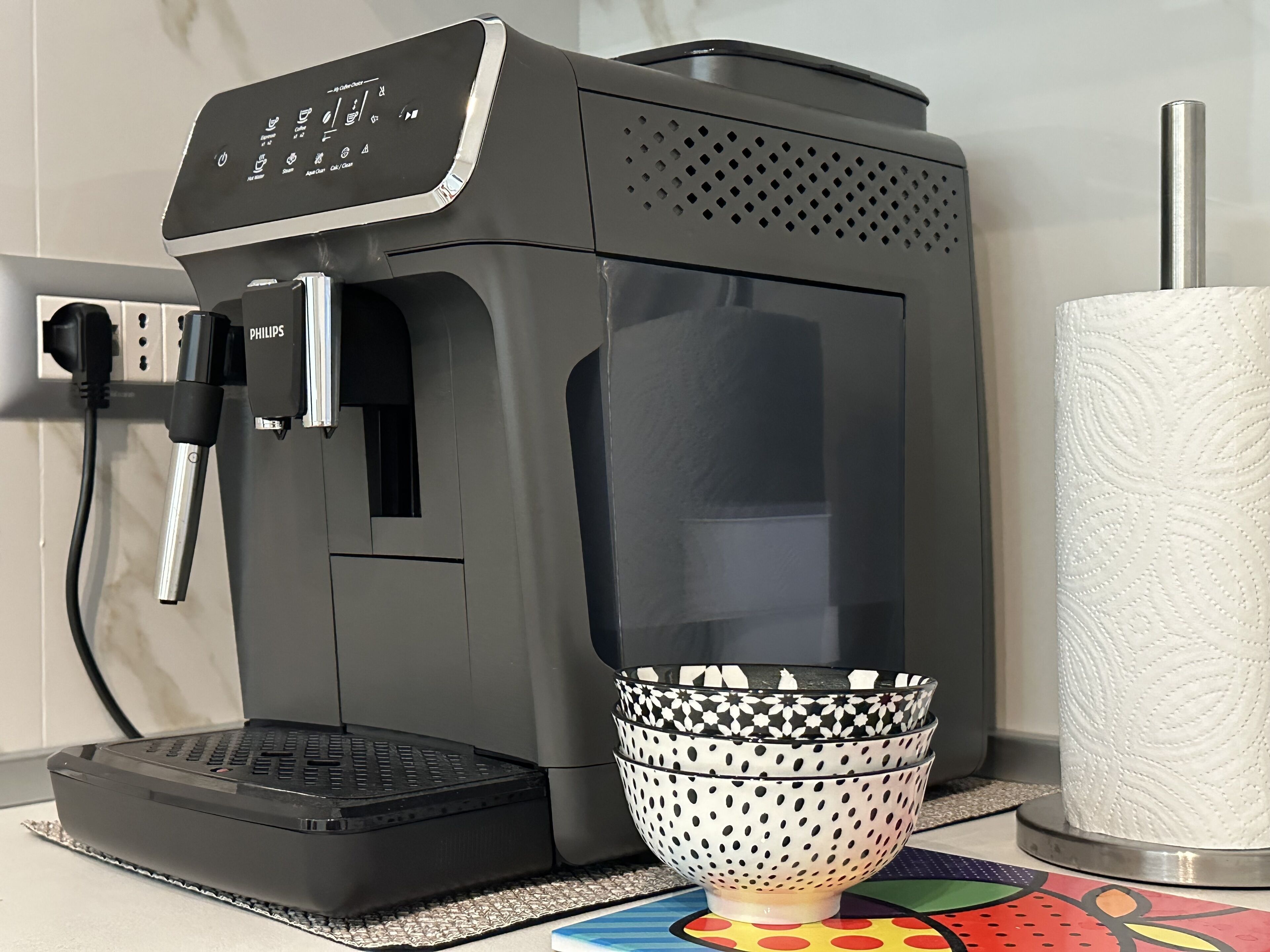 Een koffieapparaat met bedieningspaneel, een handdoekhouder en een decoratieve schaal.
