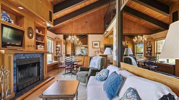 A cozy living room with a fireplace, a television, and a dining area with chairs and a table. - St Francis Townhome with Amenities, near the lake (Tahoe City)