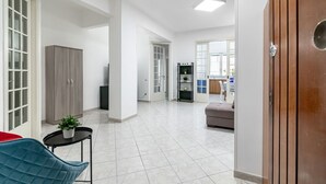 Ein geräumiger Wohnbereich mit einer Couch, einem Tisch mit Pflanze und einem Kleiderschrank.