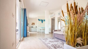 Una sala de estar moderna con un ventanal grande, un sofá, una mesita de centro y una planta decorativa.