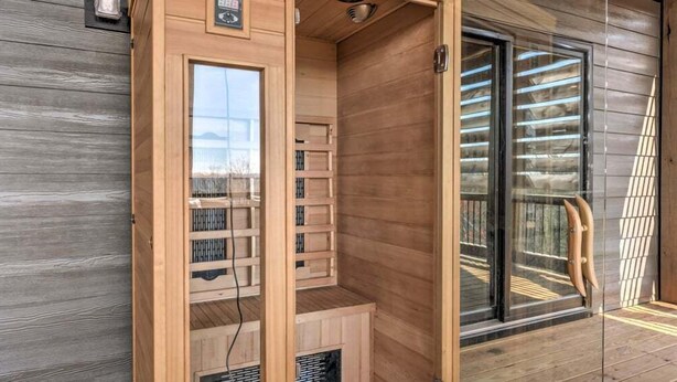 Un sauna avec des murs en bois, une porte en verre, un banc et un système de ventilation.