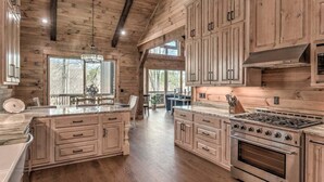 A spacious kitchen with wooden cabinetry, a large island, and a gas stove.