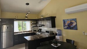 A modern kitchen with dark cabinets, stainless steel appliances, a central island, and a ceiling fan.