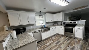 Una cocina moderna con gabinetes blancos, una estufa de acero inoxidable y una encimera de granito.