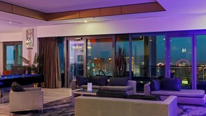 A modern living room with a pool table, comfortable seating, and large windows offering city views. - The VIBE PALMS PLACE PENTHOUSE  (Las Vegas)