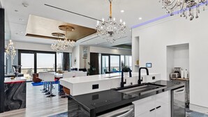 A modern kitchen with a central island, stainless steel appliances, and a view of the city. - The VIBE PALMS PLACE PENTHOUSE  (Las Vegas)