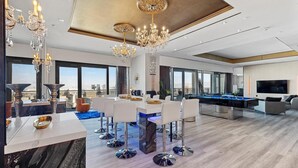 A spacious living area with a pool table, modern furniture, and large windows offering a city view. - The VIBE PALMS PLACE PENTHOUSE  (Las Vegas)