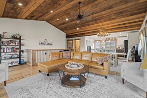 A spacious living area with a large leather sectional sofa, a round coffee table, and a wooden ceiling with exposed beams.