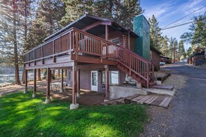 A two-story wooden cabin with a balcony, a covered porch, and a staircase leading to the upper level.