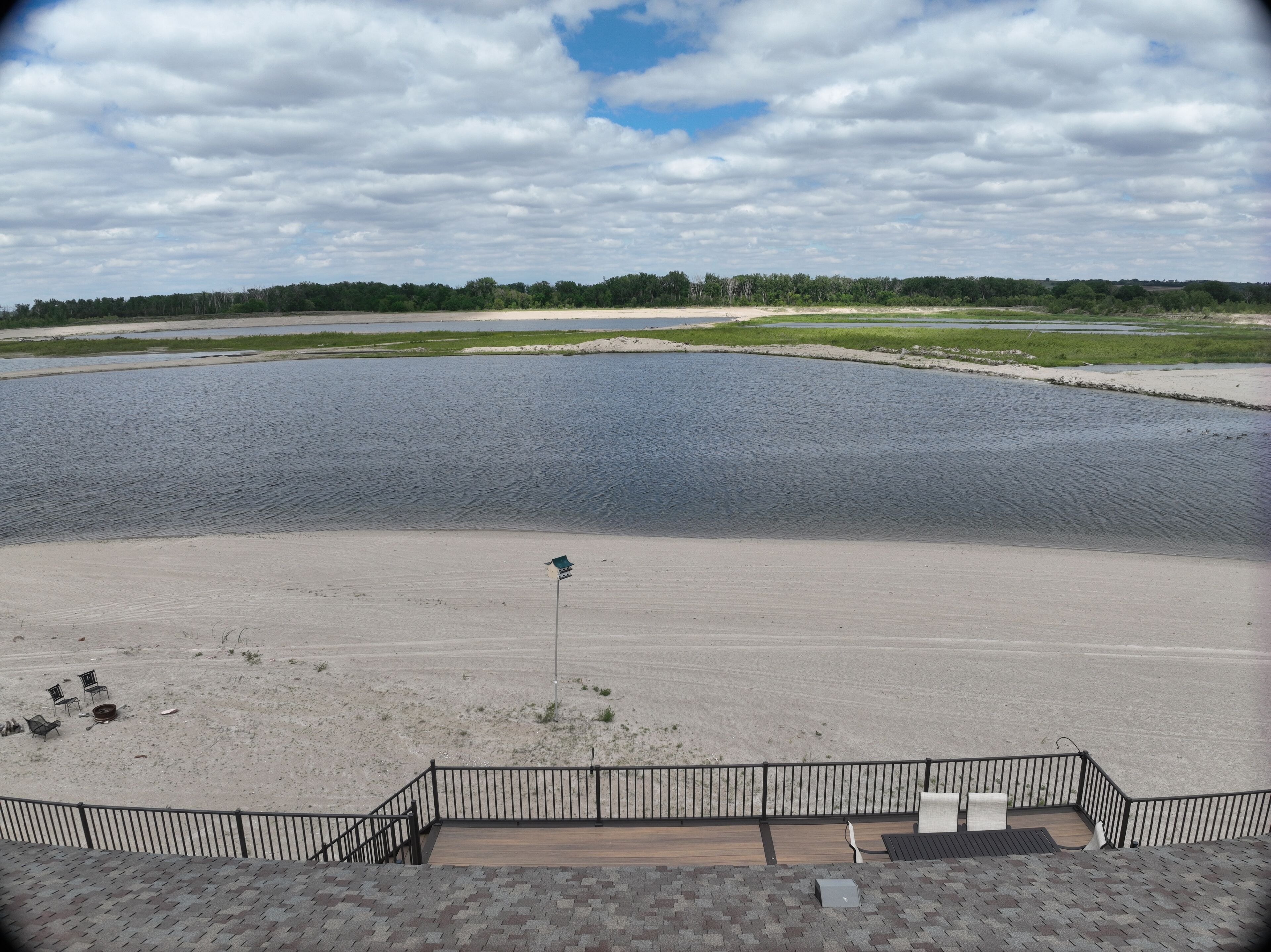 Une vue d’une vaste étendue d’eau, avec une plage de sable et un petit mât.