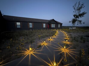Un edificio con un largo camino bordeado de luces y girasoles.
