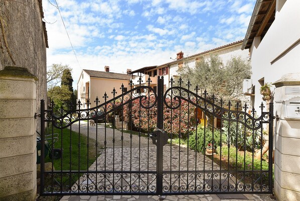 A wrought iron gate leading to a cobblestone pathway.