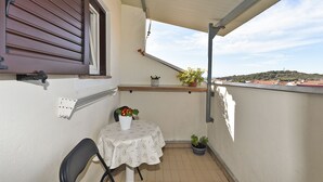 Un petit balcon avec une table, des chaises et des plantes en pot.