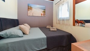 Une chambre à coucher avec un lit, des oreillers, un tableau, une fenêtre avec des rideaux et un miroir.
