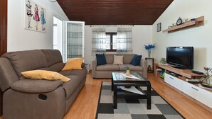 Un salon avec un canapé marron, un canapé gris, une table basse noire, un téléviseur et un plafond en bois.