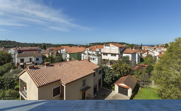 A coastal town with terracotta-tiled buildings, a clear sky, and a view of the sea.