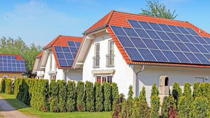 A row of houses with solar panels on the roofs, neatly trimmed hedges, and a clear sky. - Stunning home in Verchen with WiFi (Verchen)