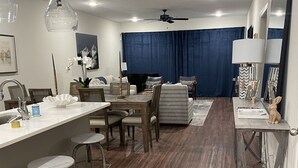 Una cocina moderna con una isla central, taburetes de bar y un área de comedor con un sofá y sillas.