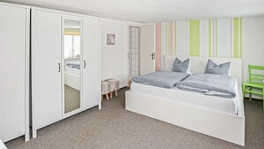 A bedroom with a bed, a wardrobe, a chair, and a striped wall. - Ferienhaus Röbel/Müritz (Röbel/Müritz)