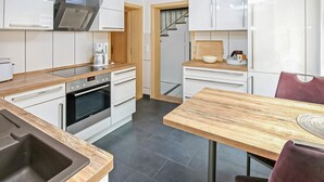 A modern kitchen with white cabinets, a built-in oven, and a wooden countertop. - Ferienhaus Röbel/Müritz (Röbel/Müritz)