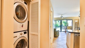 A laundry area with a washing machine and dryer, a kitchen with a dishwasher, and a view of a patio with outdoor furniture. - SUMMER DISCOUNT-- 10% discount on the room rate for Aug. Sept. Just ask Barb. (Kihei)