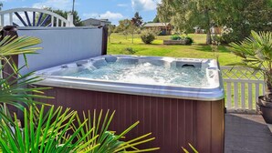 A hot tub in an outdoor setting with a wooden deck and surrounding greenery. - Ferienwohnung Neppermin/Usedom (Neppermin/Usedom)
