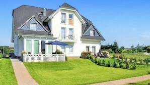 A two-story house with a large front lawn, a driveway, and a white picket fence. - Ferienwohnung Neppermin/Usedom (Neppermin/Usedom)