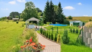A garden with a gazebo, a swimming pool, and a brick pathway. - Ferienwohnung Neppermin/Usedom (Neppermin/Usedom)