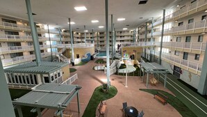 Un atrium intérieur à plusieurs niveaux, doté de balcons, d’un espace piscine central et de coins salon extérieurs.