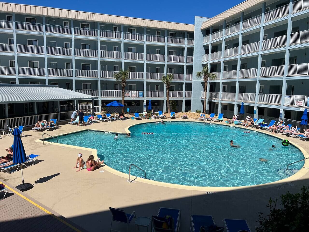 Un hôtel doté d’une grande piscine entourée de chaises longues et de parasols.