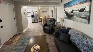 Un salon comprenant un canapé, un fauteuil inclinable, une table basse et un tableau accroché au mur.