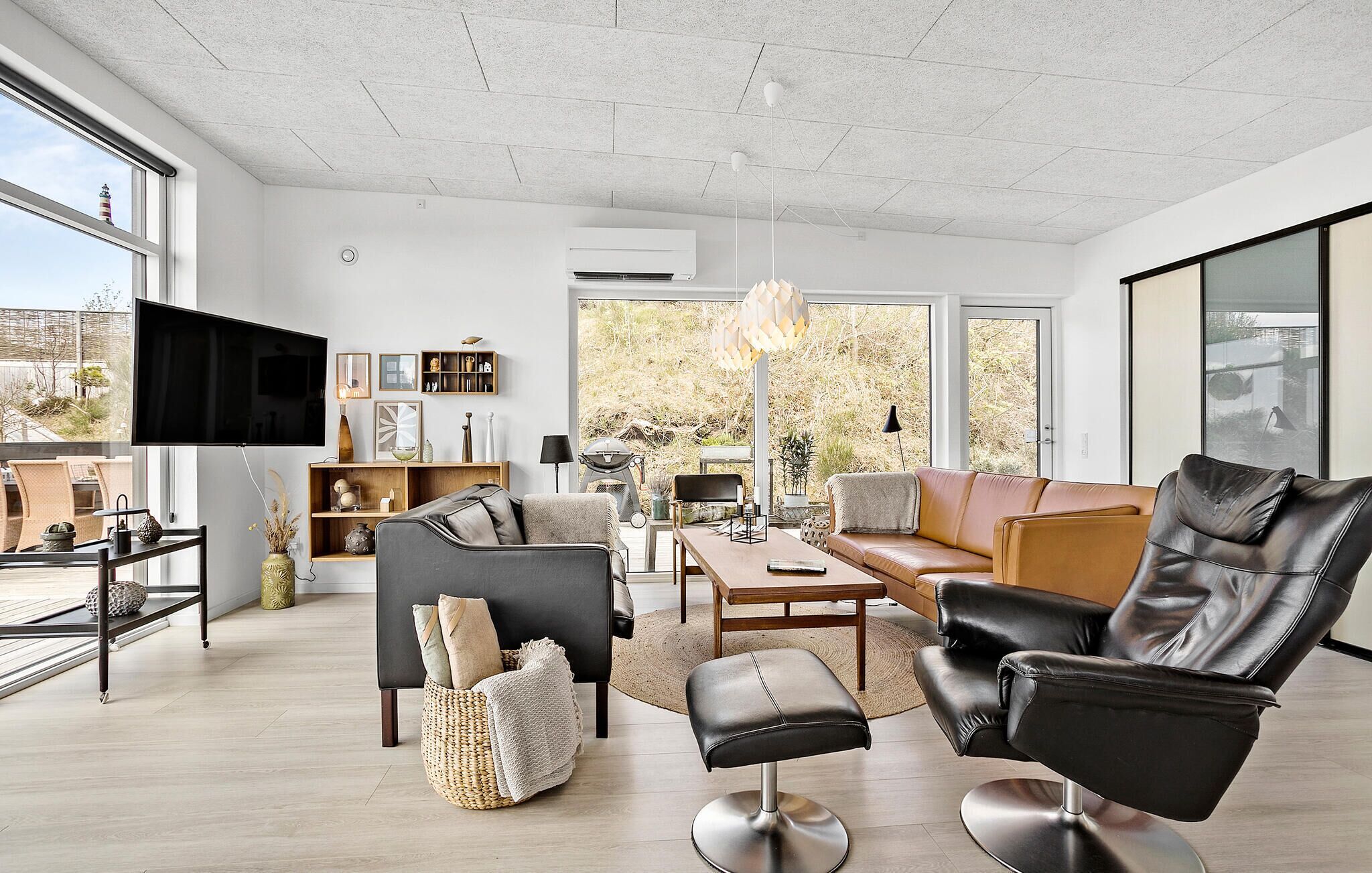 Een ruime woonkamer met een grote televisie, comfortabele zitplaatsen en uitzicht op de omgeving.