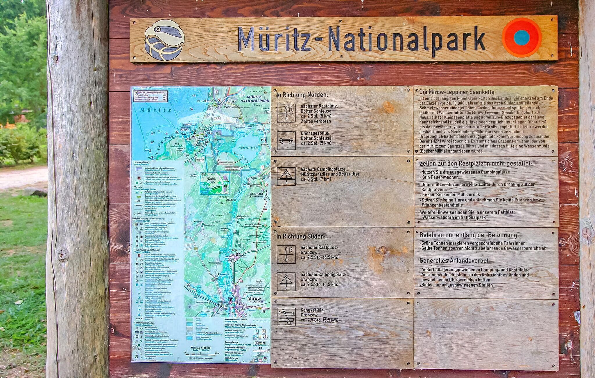 A wooden signboard for Müritz-Nationalpark with a map and directional information.