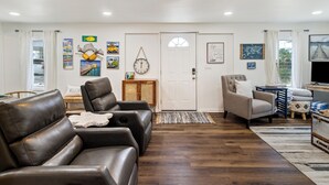 A living room with leather sofas, a wooden coffee table, and various wall decorations. - "Recuperation Cottage" offers gulf views and is steps to the beach! Pet-friendly, boat parking (Port Saint Joe)