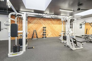A gym with weightlifting equipment, a pull-up bar, and a wooden wall.