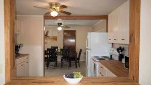 A kitchen with wooden cabinets, a white refrigerator, a stove, and a ceiling fan. - All Season Fully Furnished Home (Waskish)