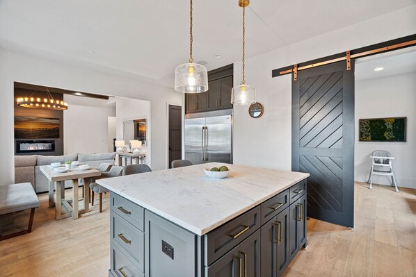 A modern kitchen with a marble island, stainless steel appliances, and a sliding barn door.