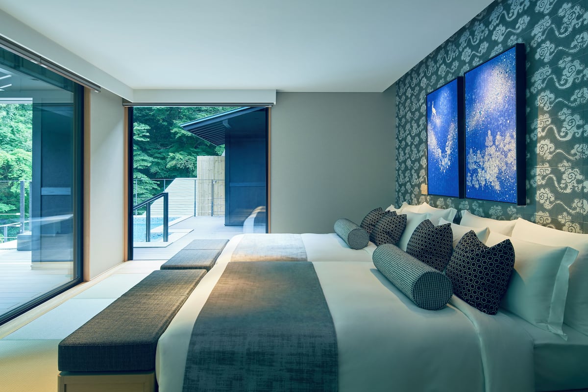 A modern bedroom with a large bed, a view of the outdoors, and a patterned wall.