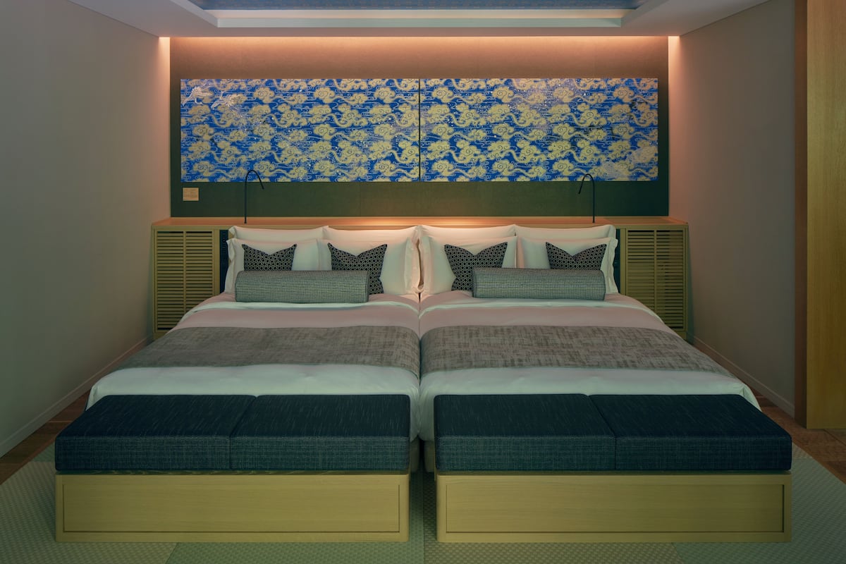 A double bed with a headboard, two bedside tables, and a large decorative wall piece above.
