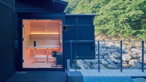 A modern building with a wooden interior and a view of a rocky riverbank. - ESPACIO The Hakone Geihinkan Rin-Poh-Ki-Ryu (Hakone)