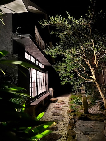 A traditional Japanese-style building with a wooden exterior and a stone pathway leading to a wooden bench.