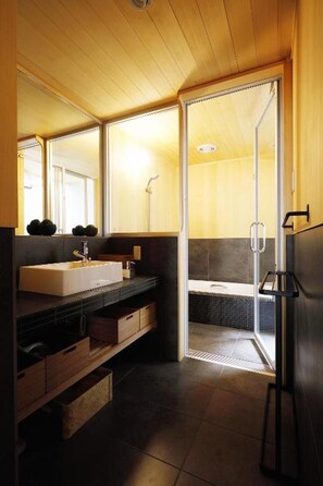 A modern bathroom with a wooden ceiling, a large mirror, a sink, and a shower area.