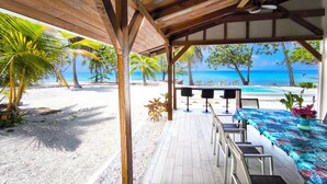 A covered outdoor seating area with a view of the beach and ocean.