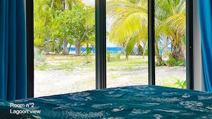 A room with a view of a lagoon and palm trees.
