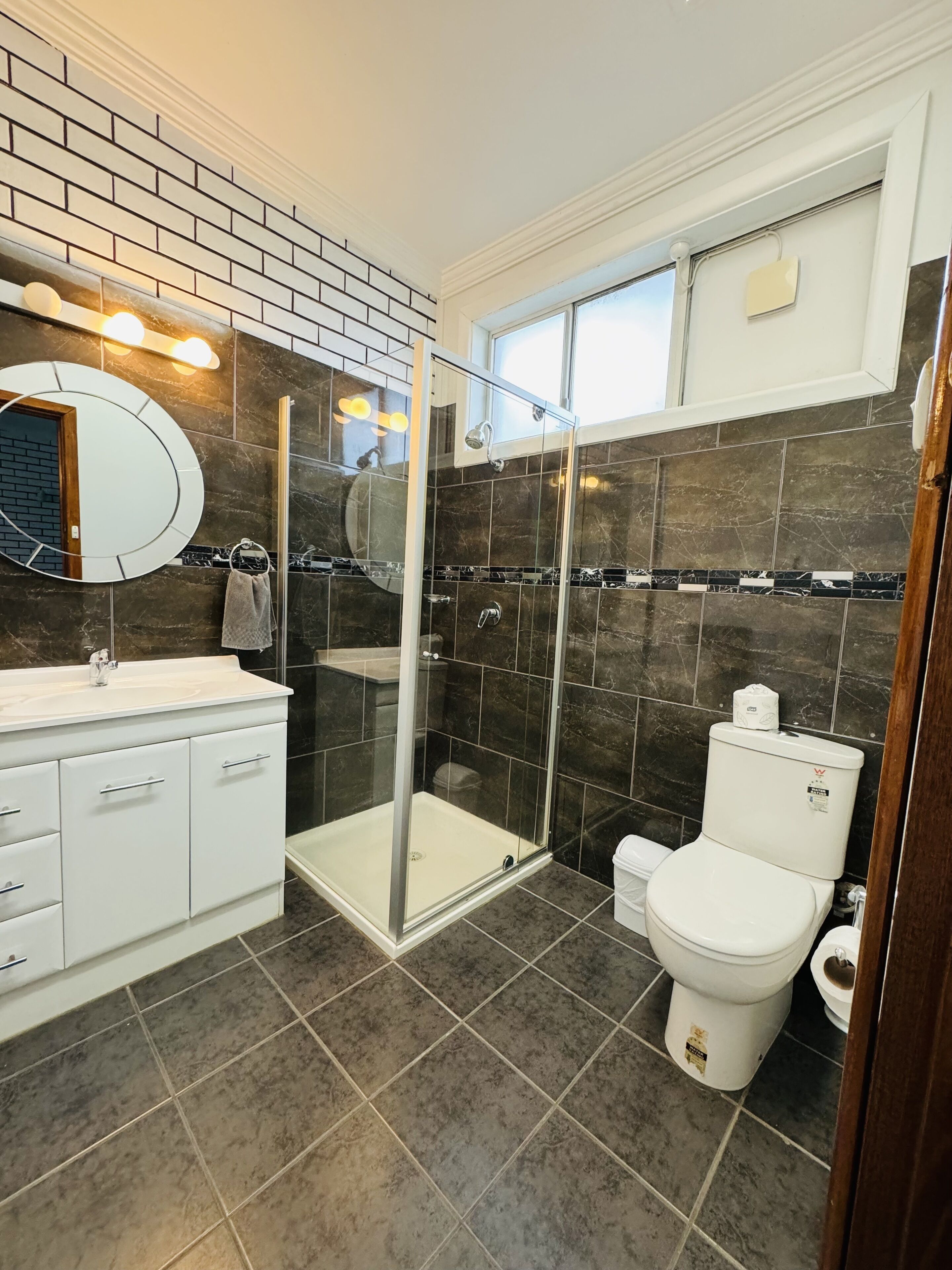 A modern bathroom with a glass-enclosed shower, a white sink, and a toilet.